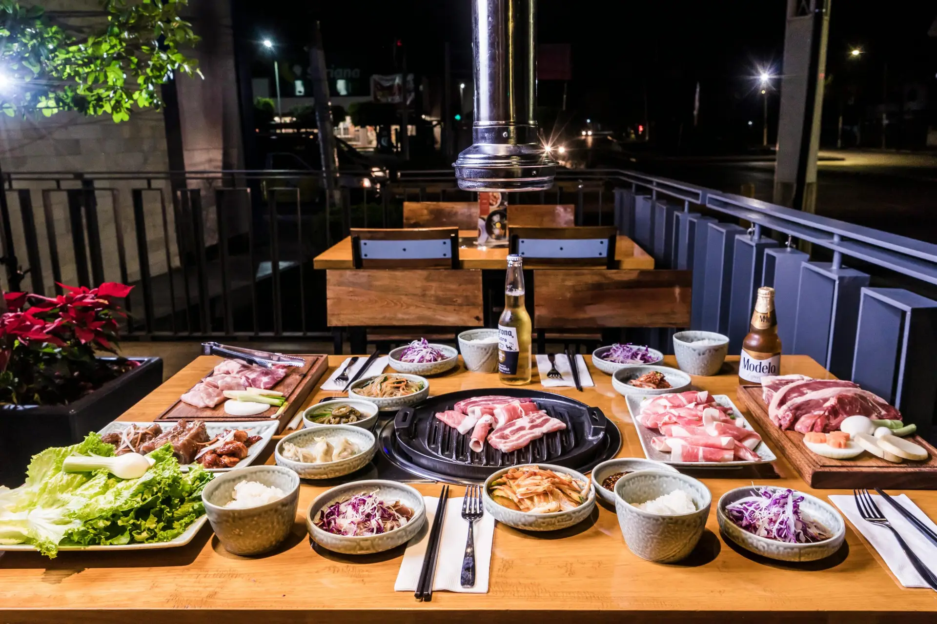 Korean Restaurant, the table in focus is set up with bbq beef and vegetables at the centre of the table bbq beef is set on top of the grill