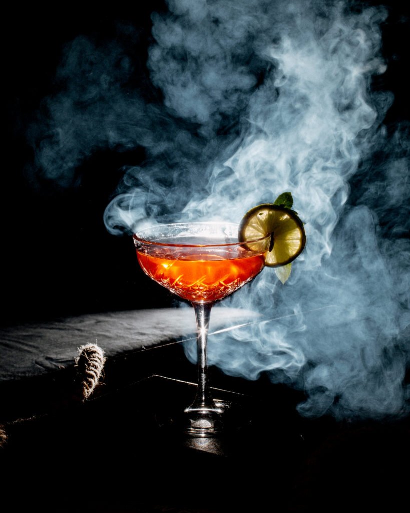 Refreshing sweet Cocktail drink in a cocktail glass with a dark smokey background