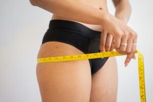 75 Hard Not Losing Weight. A woman tracking her 75 hard fitness progress by measuring her hips with a tape measure.